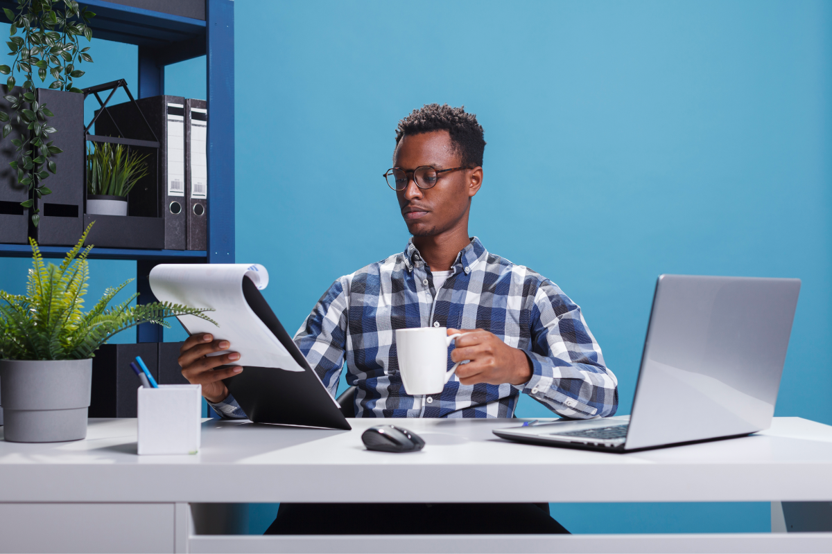 company office worker having documentation clipboard coffee cup looking project management charts young african american employee sitting modern workspace while reviewing paperwork